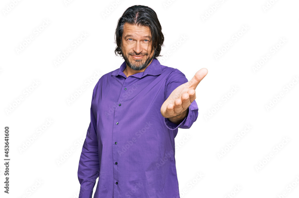 Middle age handsome man wearing business shirt smiling friendly offering handshake as greeting and welcoming. successful business. Middle age handsome man wearing business shirt smiling friendly offering handshake as greeting and welcoming. successful business.