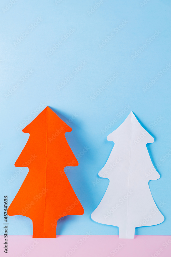 Paper Christmas trees on a blue-pink background. White and red paper christmas trees. Christmas minimal concept