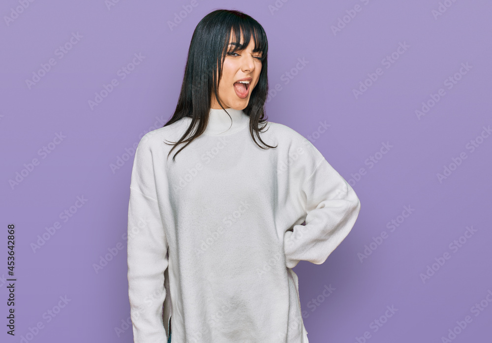 Young brunette woman with bangs wearing casual turtleneck sweater winking looking at the camera with sexy expression, cheerful and happy face. Young brunette woman with bangs wearing casual turtleneck sweater winking looking at the camera with sexy expression, cheerful and happy face.