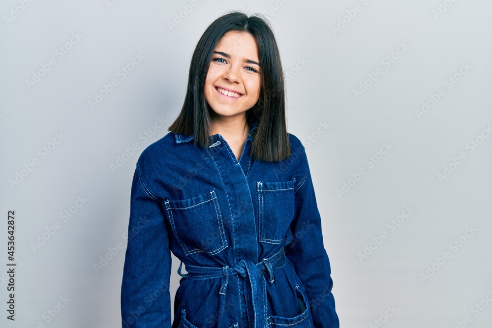 Young brunette woman wearing denim jumpsuit with a happy and cool smile on face. lucky person. Young brunette woman wearing denim jumpsuit with a happy and cool smile on face. lucky person.