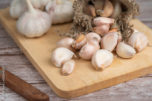 Garlic bulb and Garlic cloves on wooden chopping board.