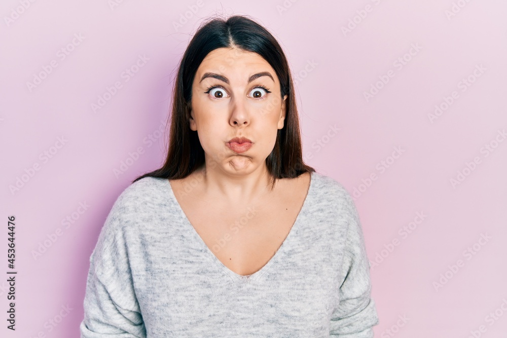 Young hispanic woman wearing casual clothes puffing cheeks with funny face. mouth inflated with air, crazy expression. Young hispanic woman wearing casual clothes puffing cheeks with funny face. mouth inflated with air, crazy expression.
