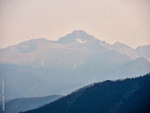 Rocky Mountains and forest trees shrouded in haze and smoke due to burning forest fires