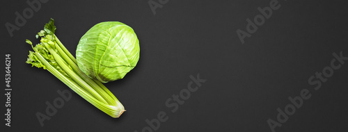 Fotografia Celery branch bunch and green cabbage isolated on black banner