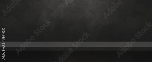 Empty shelf on a black concrete wall. Background template. Horizontal banner