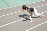 Top view of beautiful young African woman in sports clothing running on track outdoors