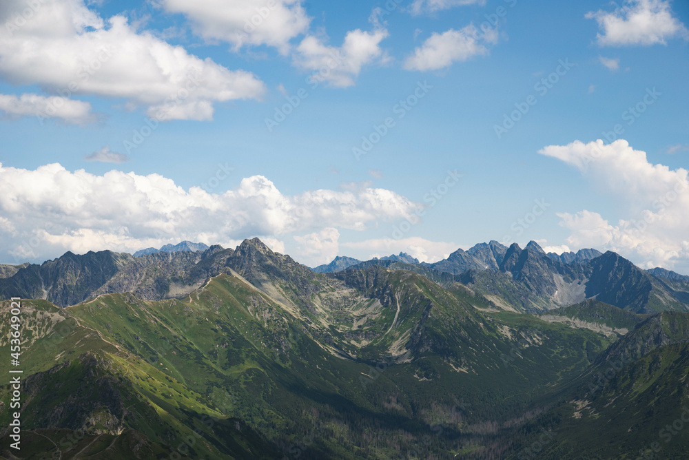 Aerial view of polish tatra peaks in the foreground, highest Slovakian peaks visible in the background with blue cloudy sky
