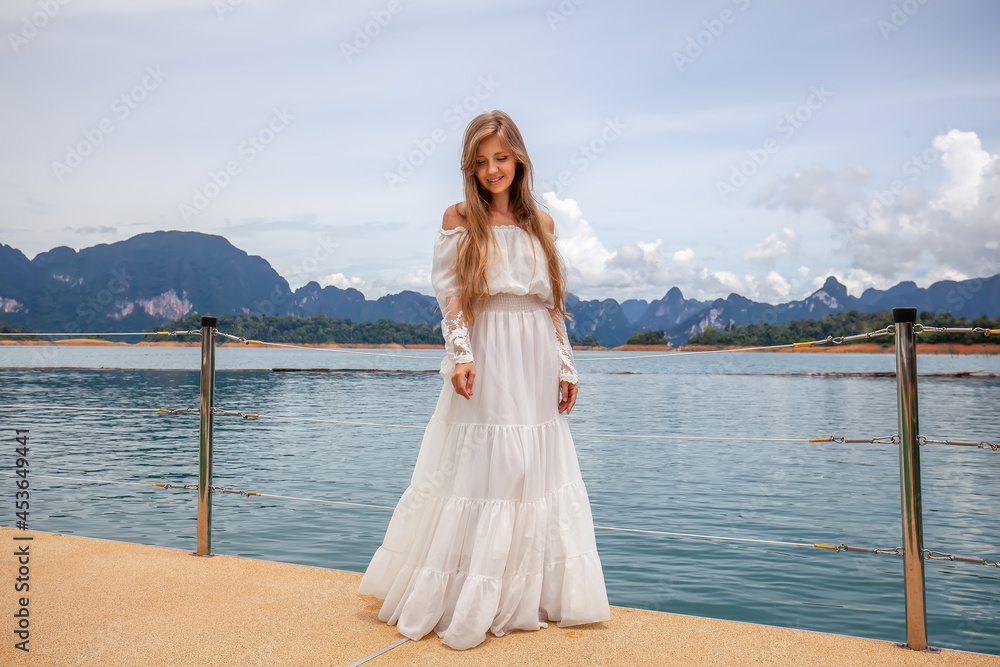 Happy Travel Girl Fun on Wooden Pier with Lake, Rainforest Jungle and Mountains on Background. Female Tourist Enjoy Vacation Cheow Lan Lake in Khao Sok National Park in Thailand Happy Travel Girl Fun on Wooden Pier with Lake, Rainforest Jungle and Mountains on Background. Female Tourist Enjoy Vacation Cheow Lan Lake in Khao Sok National Park in Thailand