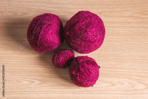 Ovillos de lana granate de diferentes tamaños sobre un fondo de madera. Crochet, ganchillo. Bolas de hilo. Madejas.