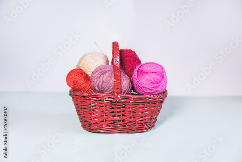 Conjunto de ovillos de lana rosa en una cesta de mimbre sobre fondo blanco. Agujas de tejer. Crochet, ganchillo. Bolas de hilo. Madejas photo