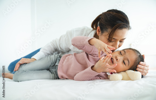 Mother having with their little daughter on bed room spending time at the holiday , happy family concept.