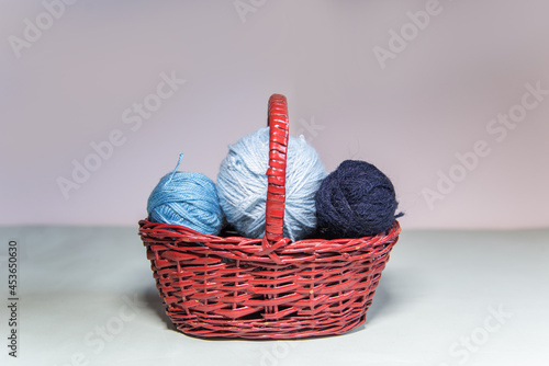 Conjunto de ovillos de lana azul en una cesta de mimbre sobre fondo blanco. Agujas de tejer. Crochet, ganchillo. Bolas de hilo. Madejas