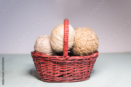 Conjunto de ovillos de lana marrón en una cesta de mimbre sobre fondo blanco. Agujas de tejer. Crochet, ganchillo. Bolas de hilo. Madeja