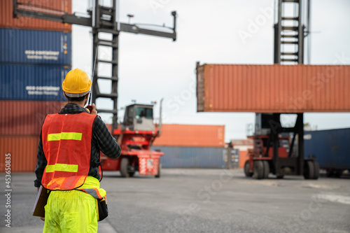 Engineer  use walkie-talkie in order to control container from Cargo freight for import and export.