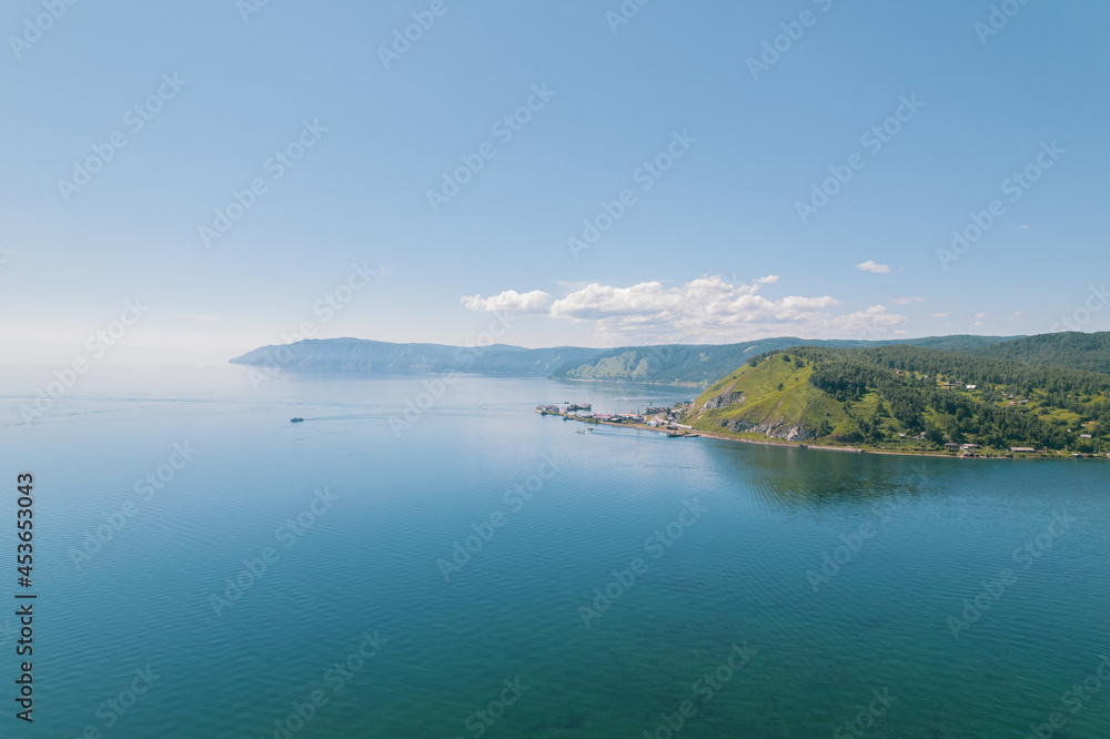 Obraz premium Lake Baikal is a marvelous blue jewel framed by scenic mountains and forests. Epic cinematic aerial view Lake Baikal. Aerial view of blue lake and green forests.