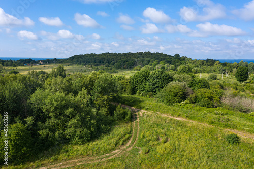 Path through summer field and forest near farmland. Aerial view