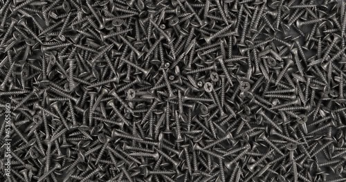 Rotation. Falling screws onto a pile of black screws. Industrial background.