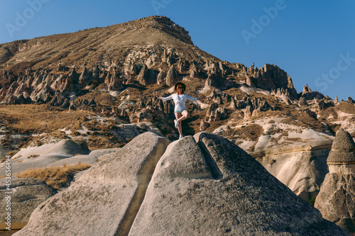 Traveler girl  tourist posing  Meditation  vyoga pose. Fairy chimneys park in the background. rock formations. Travel and vacation  tour Goreme  Cappadocia  Turkey.