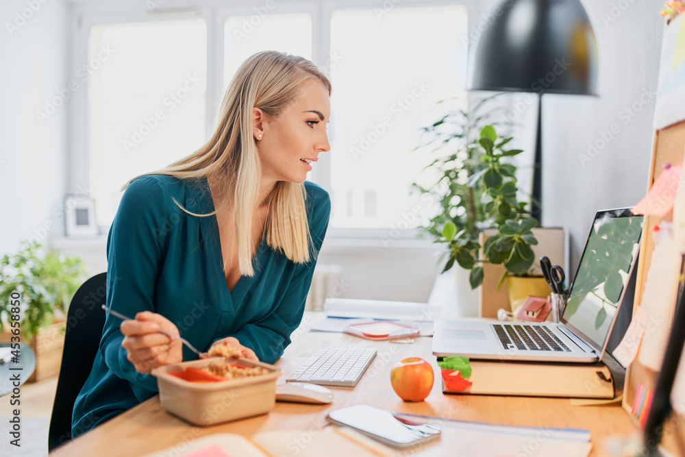 Young woman eating lunch while working from home office Stock Photo | Adobe  Stock