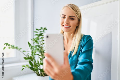Young woman having video call on smartphone from home © baranq