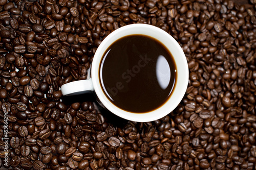 Coffee cup top view on roasted coffee beans background