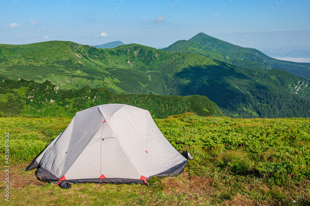 A gray tent stands in a clearing in the Carpathians overlooking Hoverla - the highest mountain of the Ukrainian Carpathians

