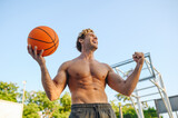 Young muscular strong sportsman man naked torso shoot free throw jump high train hold in hand ball do winner gesture clench fist at basketball game playground court Outdoor courtyard sports concept.