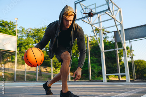 Young sporty strong confident caucasian serious sportsman man 20s wear grey dark sportswear clothes dribbling training with ball at basketball game playground court. Outdoor courtyard sports concept © ViDi Studio