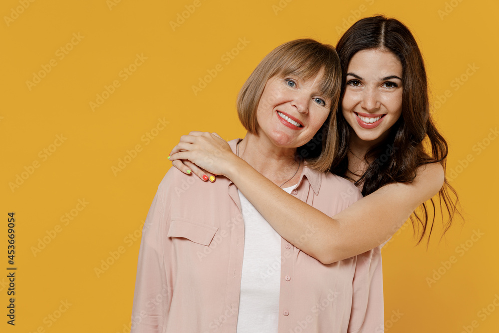 Two young smiling satisfied daughter mother together couple women wearing casual beige clothes look camera hugging isolated on plain yellow color background studio portrait. Family lifestyle concept. Two young smiling satisfied daughter mother together couple women wearing casual beige clothes look camera hugging isolated on plain yellow color background studio portrait. Family lifestyle concept.