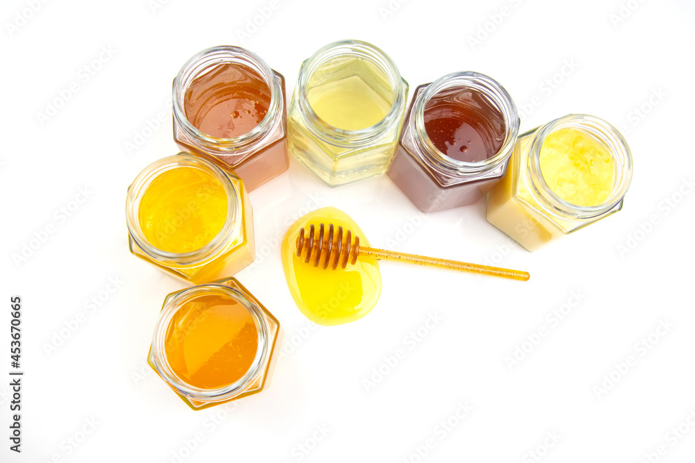 spoon with fresh honey and jars with different types of honey on a white background. organic vitamin food spoon with fresh honey and jars with different types of honey on a white background. organic vitamin food
