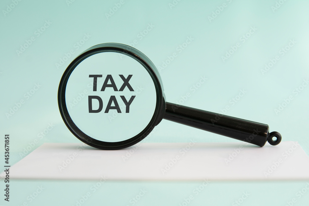 Inscription TAX DAY on magnifying glass, concept Inscription TAX DAY on magnifying glass, concept