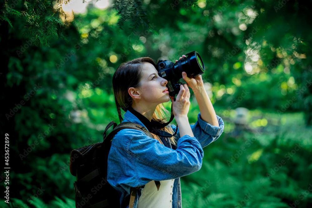 young girl with a camera and a backpack in the park