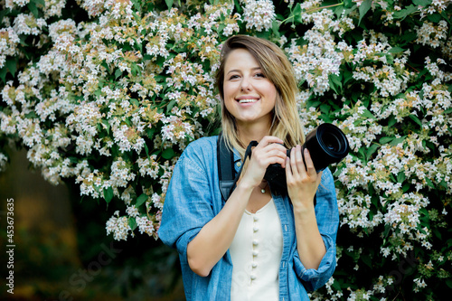 style woman with camera near blooming tree in a grarden in spring time photo