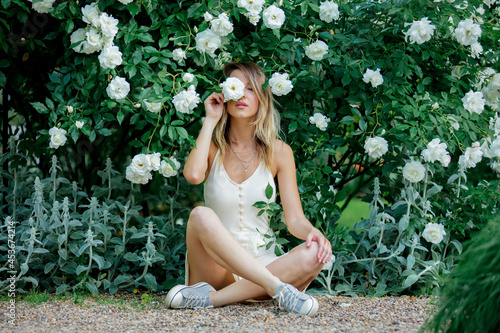 style woman near white roses in a grarden in spring time photo