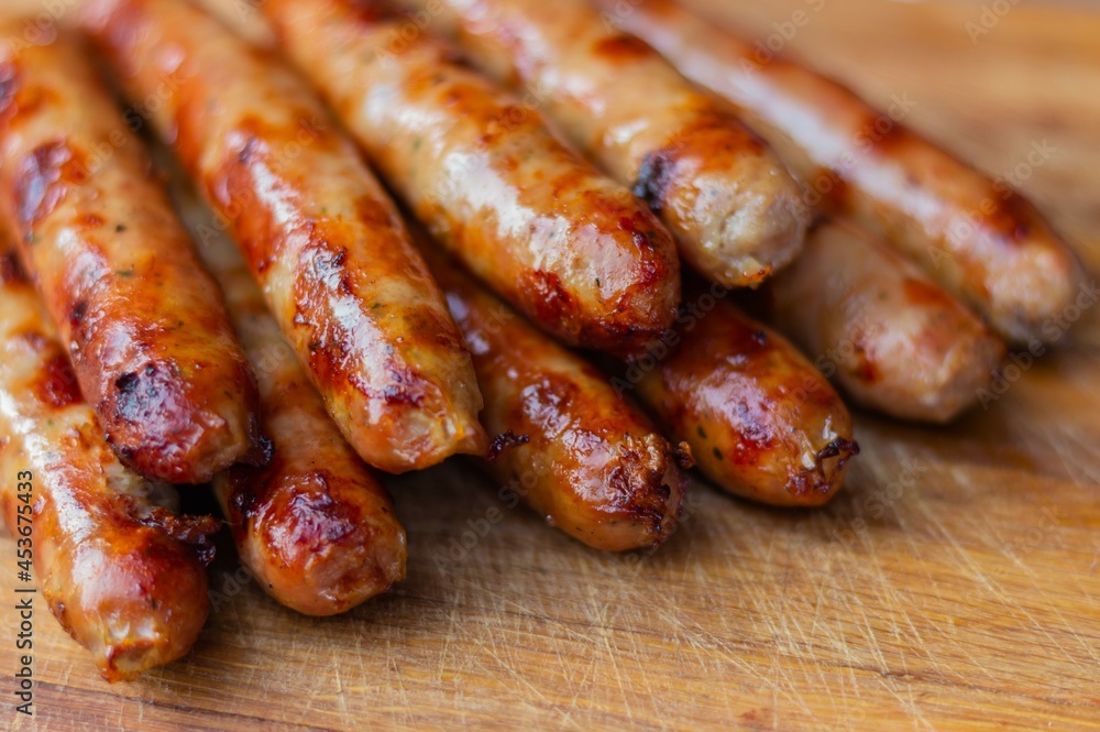 Seven appetizing toasted sausages with turkey lie on a wooden board. Photo at an angle Seven appetizing toasted sausages with turkey lie on a wooden board. Photo at an angle