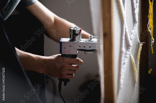 Cropped view of artisan making carpet with pattern on canvas in frame 