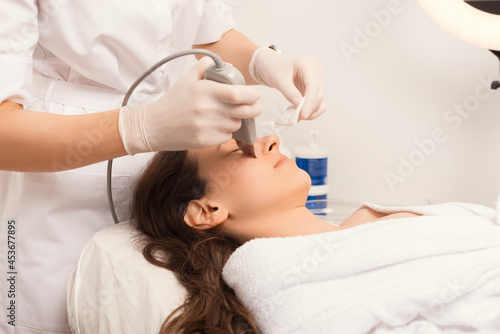 Process of the ultrasound cleaning procedure for skin of the face, made in a white salon.