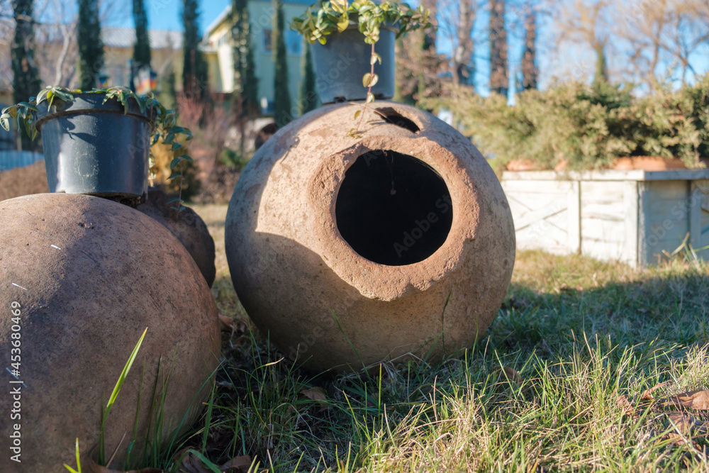Georgian traditional ancient jug for wine qvevri on the ground lit by sunlight Georgian traditional ancient jug for wine qvevri on the ground lit by sunlight