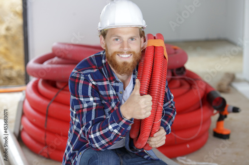 builder transporting pipes while showing thumb up photo