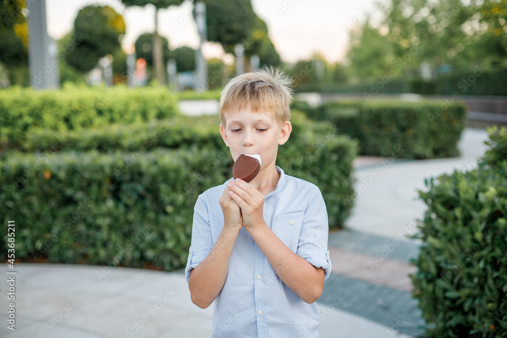 Fototapeta premium blonde boy in blue shirt eating popsicle ice cream