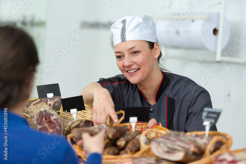 woman in uniform selling delicious smoked salami sausages