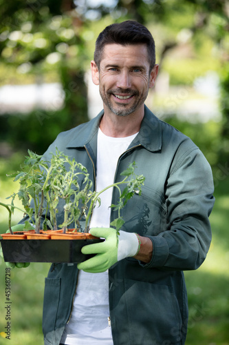 happy man transplanting a new plant in his garden