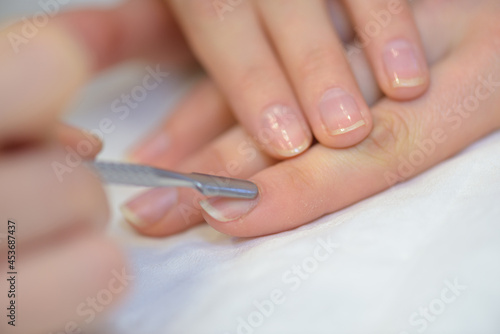 manicurist filing persons nails in salon