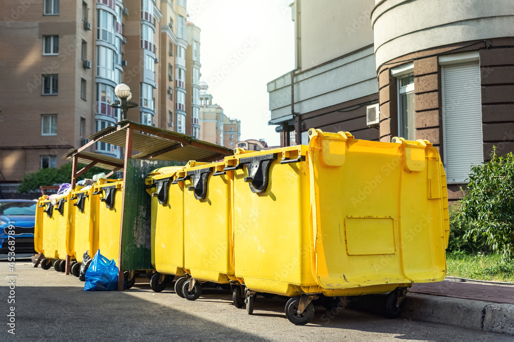 Rows of many big plastic yellow dumpster cans full of black plastic