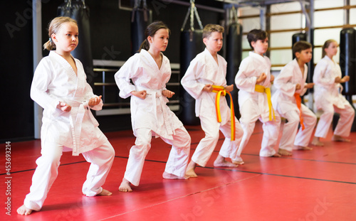 Preteen school childs together trying martial moves in karate class