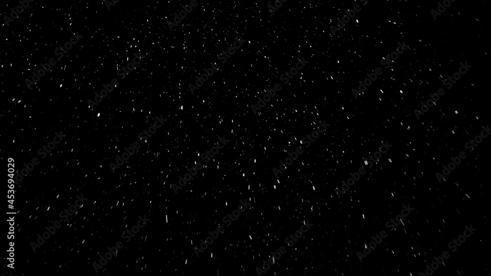Small snowflakes falling softly from the sky from left to right and then changing their way because of the wind. Beautiful snowfall isolated on the black background.