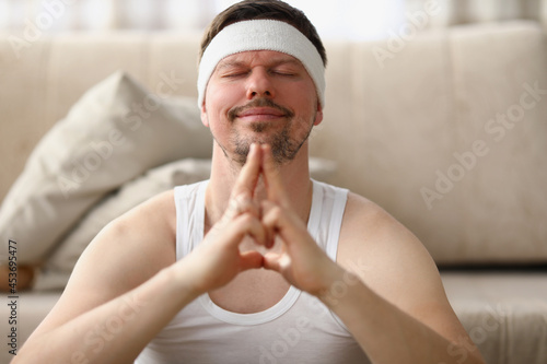 Man meditates while sitting on the floor at home