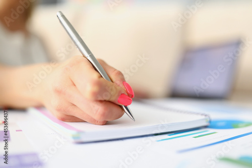 Womans hand taking notes with silver pen close-up