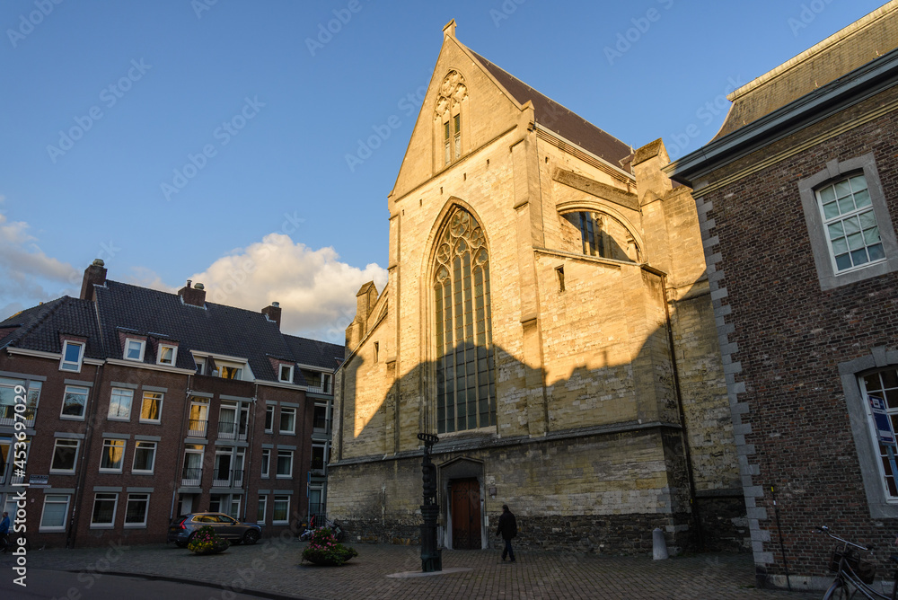 Outdoor sunny street view of Oude Minderbroederskerk, Catholic church, in old town Maastricht, Netherlands during sunset time.
