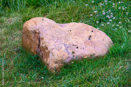 Heart shaped pink weathered rock in a green lawn, as a nature background 